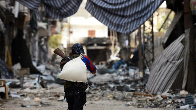 Rebelde carrega saco de areia, na Síria