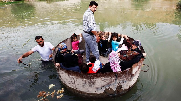 Sírios cruzam a fronteira com a Turquia pelo rio Orontes, perto da vila de Hacipasa. Dezenas de civis sírios, muitos deles mulheres e crianças, cruzaram o rio na tentativa de fugir dos combates