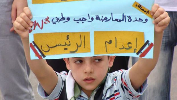 Na Síria, menino segura cartaz: "O povo da Síria quer que o presidente seja executado"