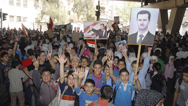 O presidente da Síria, Bashar al-Assad, cumprimenta simpatizantes na saída da votação do referendo