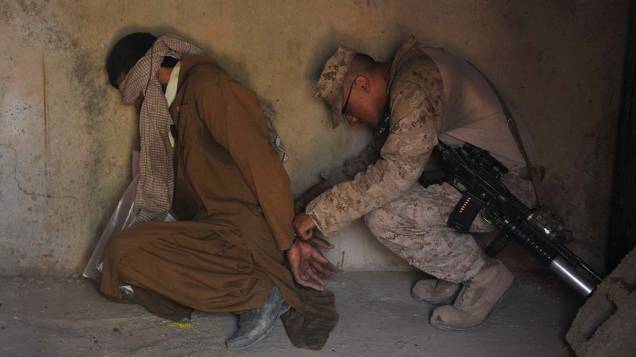 Soldado americano confere as algemas de um prisioneiro na cidade de Helmand, Afeganistão