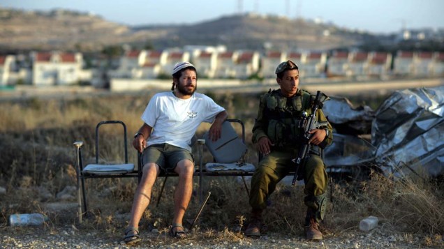 Colono judeu e soldado israelense em posto de vigilância próximo ao assentamento de Kiryat Arba, Israel