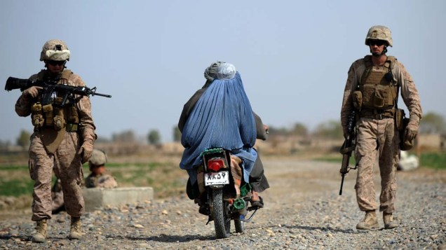 Mulher passa por soldados americanos nas proximidades do rio Helmand no Afeganistão