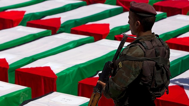 Soldado observa caixões de 91 militantes mortos que foram transferidos por Israel para a ANP