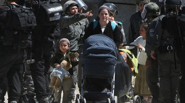 Em Hebron, soldados israelenses escoltam família que foi obrigada a deixar sua casa na região de conflito na Cisjôrdania