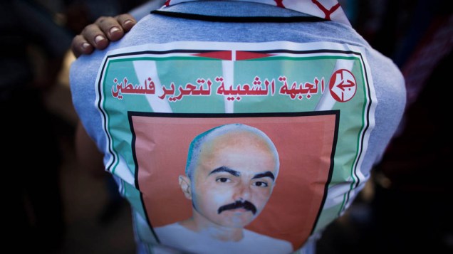 Homem exibe camiseta com o rosto de um dos prisioneiros palestinos que foi libertado hoje