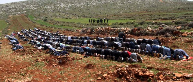 Soldados israelenses observam grupo de palestinos em oração na cidade de Nablus, Cisjordânia