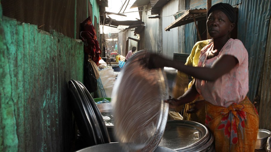 Mulher lava as bandejas usadas em uma tenda no mercado e alimentos em Juba, no Sudão