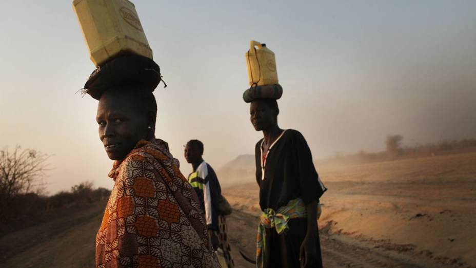 Mulheres caminham para suas aldeias carregando água da periferia de Juba, no Sudão
