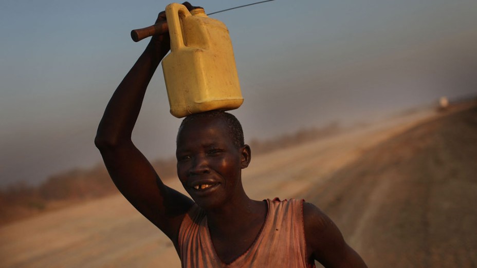 Mulher caminha para sua aldeia carregando água da periferia de Juba, no Sudão<br>
