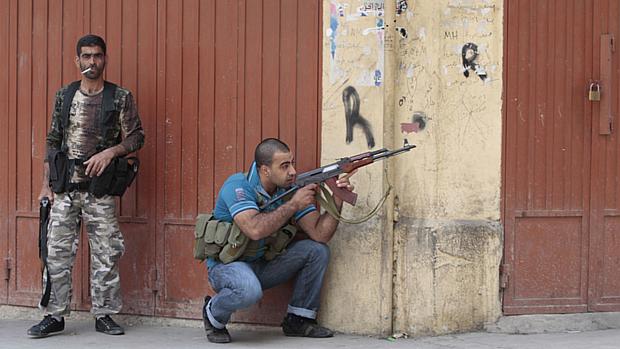 Guerrilheiro sunita se prepara para atirar contra alauítas na cidade de Trípoli, no Líbano