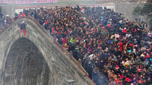 Em Mianyang, China, multidão atravessa a ponte Tai Ping, de 200 anos, durante evento em que os participantes jogam roupas velhas e moedas em busca de saúde e felicidade