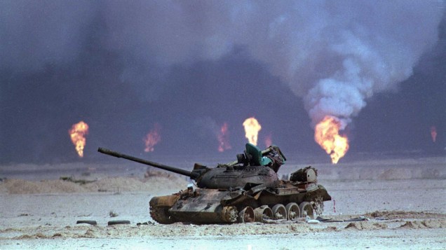 Tanque iraquiano destruído próximo a poços de petróleo incendiados no Kuwait. Tropas iraquianas saquearam, explodiram e queimara grande parte da infra-estrutura petrolífera do país durante a Guerra do Golfo