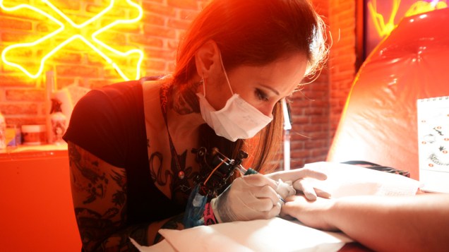 A tatuadora paulistana Akemi Higashi faz tatuagem na carioca Kaissa Oliveira, 20 anos