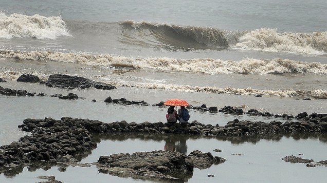 Casal indiano observa o mar em Mumbai em época de monções no país, quando chove em excesso