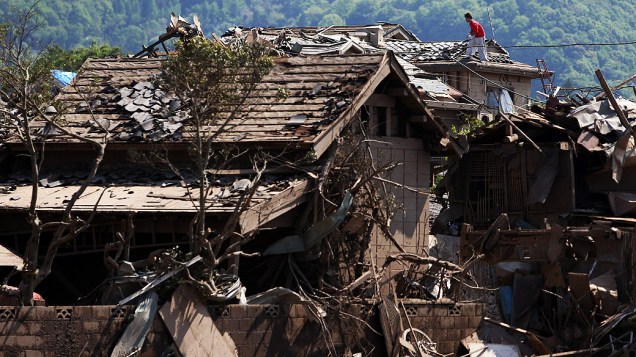 Um homem remove os restos de uma casa danificada que teve o teto destruído por um tornado em Tsukuba, no Japão