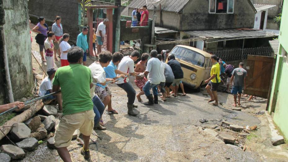 Moradores do Vale da Revolta, em Teresópolis, tentam remover carros arrastados pela força da água
