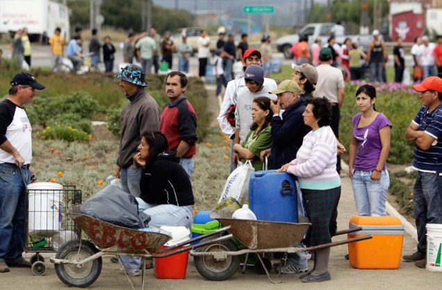Pessoas fazem fila para aguardar a distribuição de água, em Hualpen.