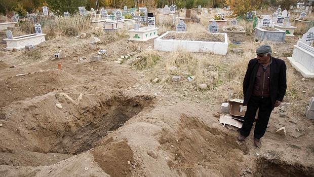 Homem visita covas de vítimas do terremoto na província de Ercis