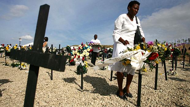 Mulher coloca flores numa cruz no cemitério improvisado de St. Cristophe, no Haiti, na terça-feira, véspera do primeiro aniversário do terremoto que arrasou o país