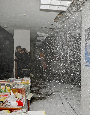 Trabalhadores se protegem de parte do teto que desabou após terremoto na cidade de Sendai.
