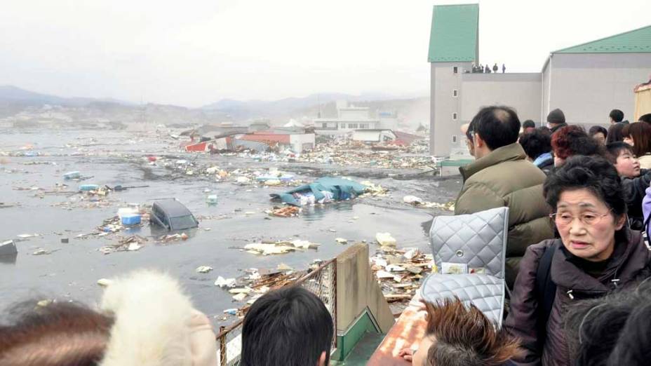 Pessoas observam a destruição do tsunami no porto de Kessennuma, Japão