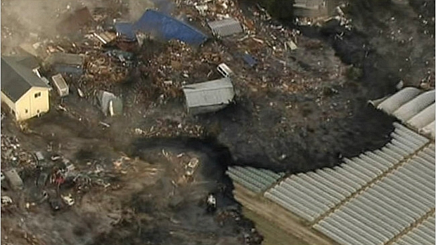 Casas são arrastadas pelas águas na cidade de Sendai, na tarde desta sexta-feira, após tsunami atingir a costa japonesa