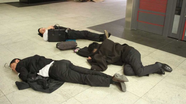 Japoneses dormem em estação de trem de Yokohama, Japão