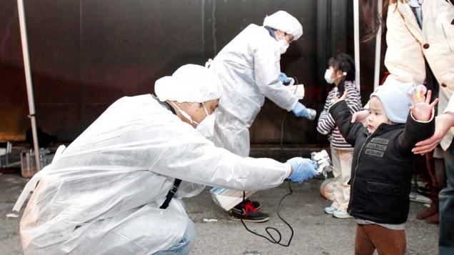 Oficiais medem nível de radiação em crianças e famílias que evacuam a área perto da usina nuclear de Fukushima Oficiais medem nível de radiação em crianças e famílias que evacuam a área perto da usina nuclear de Fukushima