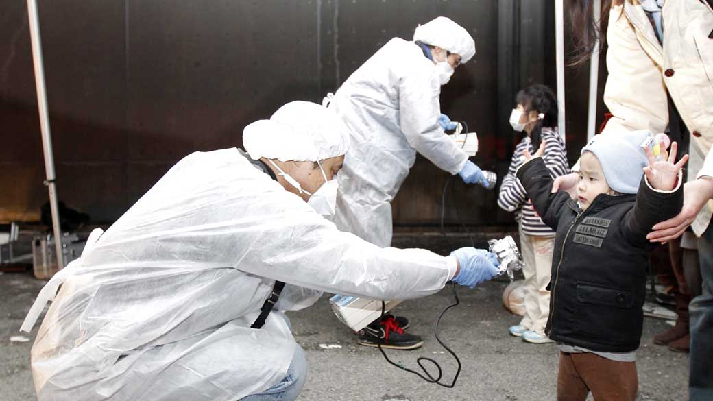 Oficiais medem nível de radiação em crianças e famílias que evacuam a área perto da usina nuclear de Fukushima