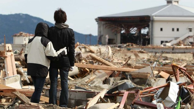 Irmãos observam a casa da família destruída em em Rikuzentakata, Japão