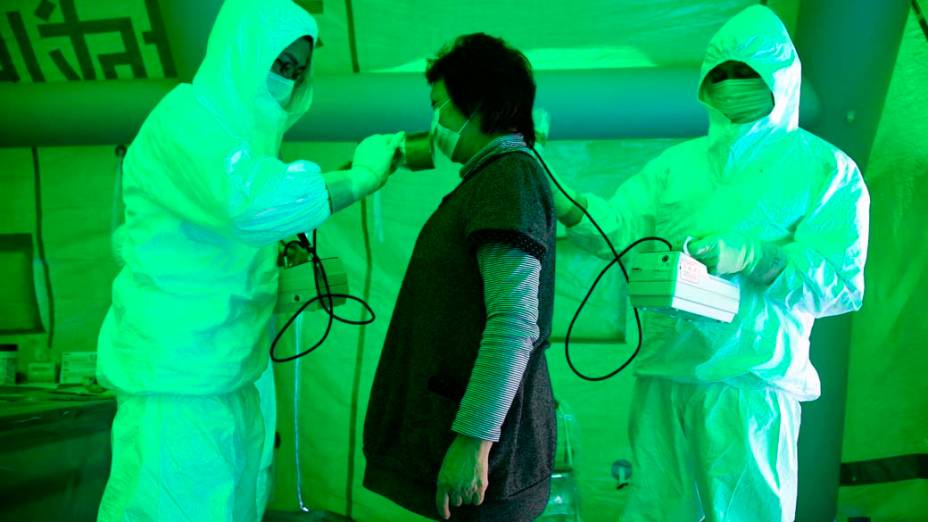 Equipe médica mede  nível de exposição a radiação nuclear em mulher na cidade de Hitachi, Japão