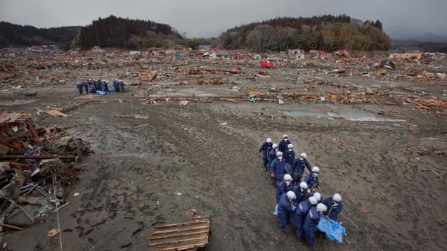 Policiais carregam corpos recuperados de escombros em Rikuzentakata, Japão