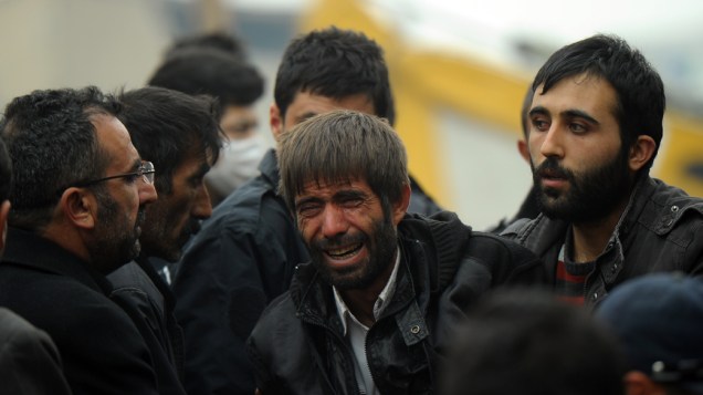 Parentes de vítimas do terremoto choram próximas a um prédio que desabou após um terremoto em Van, Turquia