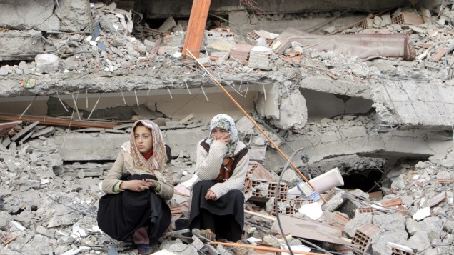 Moradoras sobre os escombros de um edifício em Ercis, Turquia