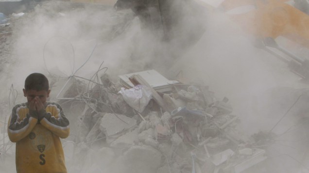 Garoto se protege da poeira durante remoção dos escombros em Ercis, na Turquia