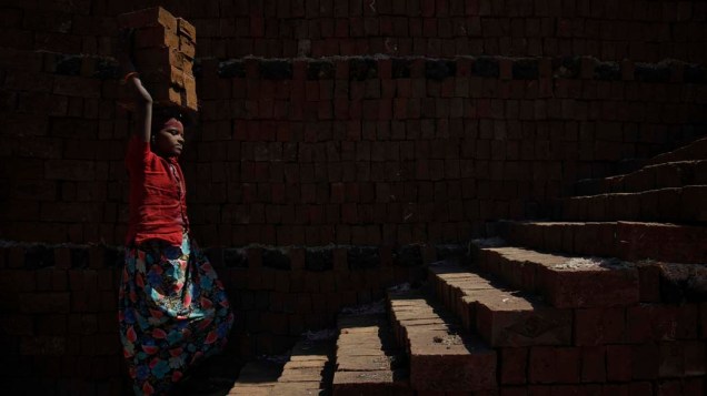 Jovem carrega tijolos para serem queimados na cidade de Karad, Índia