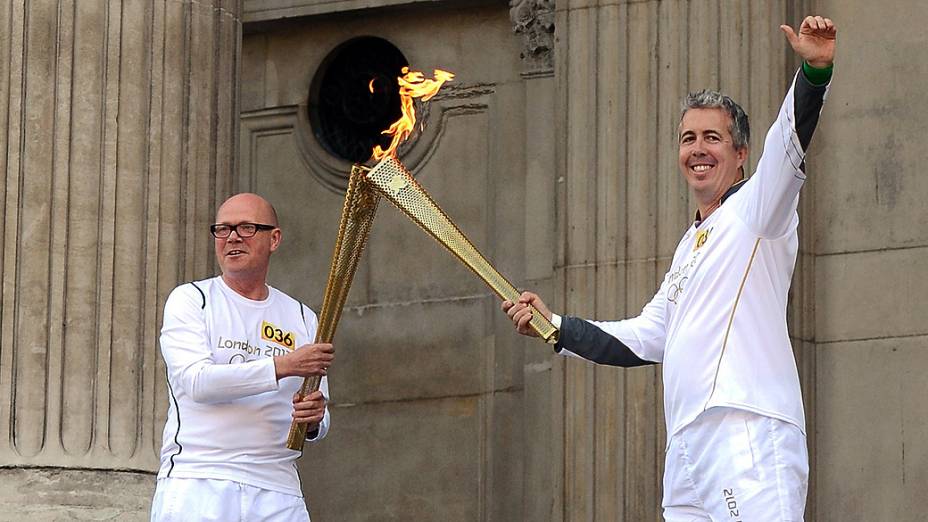 Kevin Crain passa a chama da olímpica a John Elbrow, durante a passagem da Tocha Olímpica pela Catedral de São Paulo, em Londres
