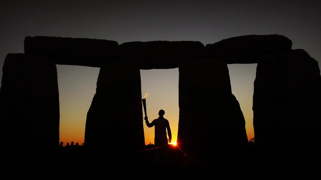 O ex-atleta olímpico Michael Johnson posa para foto com a tocha olímpica em frente às históricas pedras Stonehenge