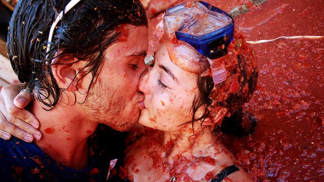 Casal se beija em meio ao molho. Foliões lotam as ruas da vila de Buñol, perto de Valência (Espanha), para comemorar a festa da Tomatina
