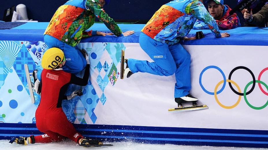A patinadora chinesa Fan Kexin cai e tromba com um membro da organização durante competição nos Jogos Olímpicos de Inverno de Sochi-2014