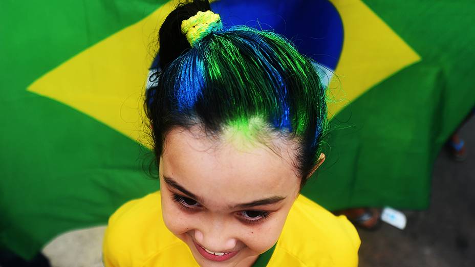 Criança pinta o cabelo com as cores da bandeira do Brasil
