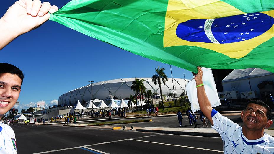 Torcedores seguram a bandeira do Brasil em frente à Arena Amazônia antes do jogo entre Inglaterra e Itália, em Manaus