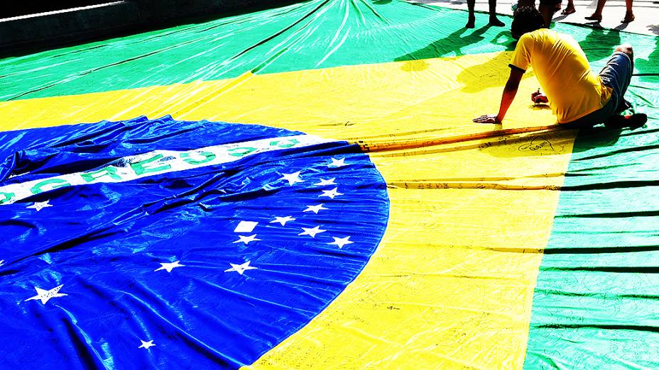 Torcedores assinam uma bandeira do Brasil antes do jogo contra a Colômbia no Castelão, em Fortaleza