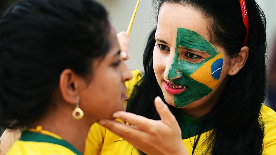 Torcedoras pintam a bandeira do Brasil no rosto antes do jogo contra a Holanda no Mané Garrincha, em Brasília