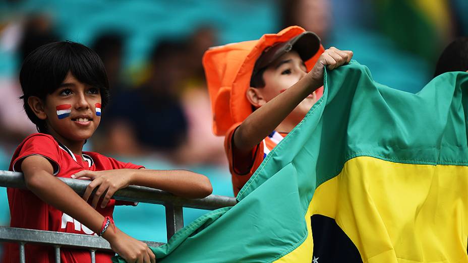 Crianças são fotografadas junto à bandeira brasileira enquanto aguardam o início da partida entre Holanda e Costa Rica, na arena Fonte Nova, em Salvador