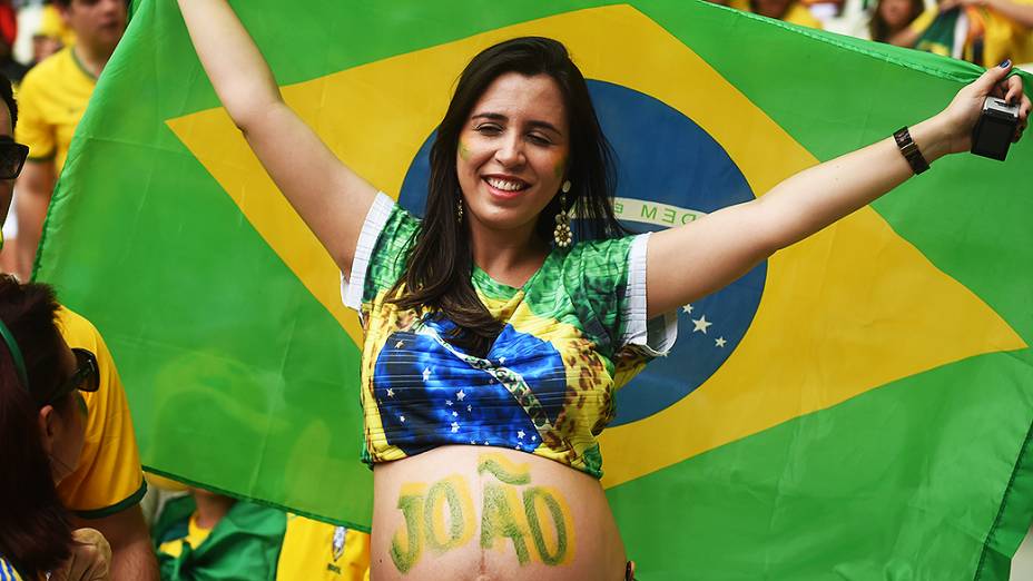 Torcedora do Brasil segura bandeira do país antes do jogo contra o México no Castelão, em Fortaleza