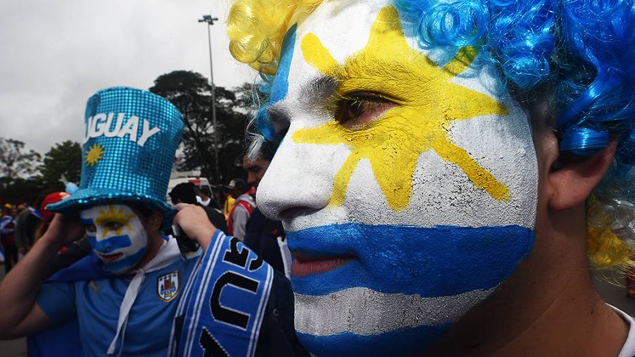 Torcedor pinta o rosto com a bandeira do Uruguai antes do jogo contra a Inglaterra no Itaquerão, em São Paulo