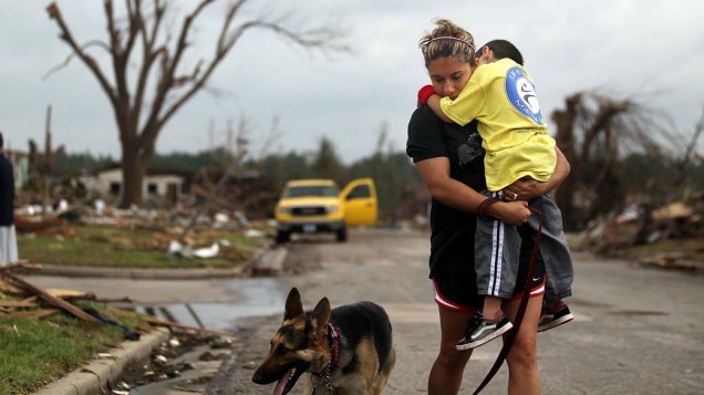 Kimmy Lankford caminha com o seu filho Jack de 5 anos em meio a destruição do bairro onde mora, após o tornado que atingiu a cidade de Joplin no estado americano do Missouri