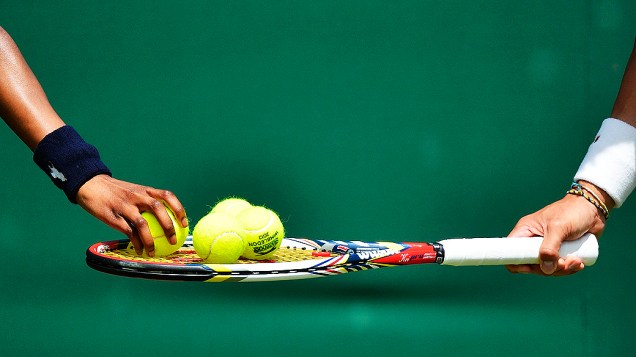 Menina coloca bolas de tênis na raquete de Kei Nishikori do Japão durante torneio de Wimbledon